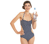 Portrait of happy young woman in swimsuit showing bottle of wate