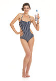 Full length portrait of happy young woman in swimsuit with bottl