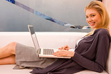 Smiling young woman using laptop sitting couch