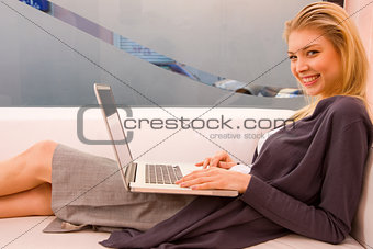 Smiling young woman using laptop sitting couch