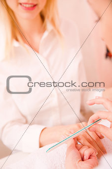 Professional manicurist giving treatment to young woman