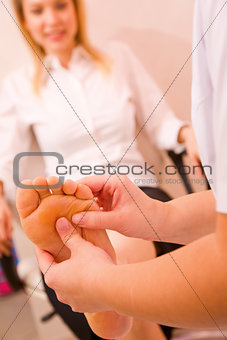 Close-up of therapist's hands massaging female foot