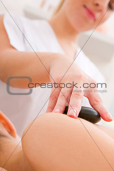 Therapist placing hot stone woman's back