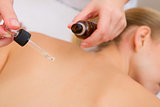 Masseuse pouring massage oil with pipette