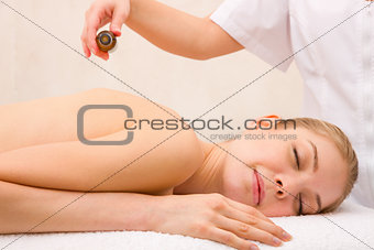 Masseuse pouring massage oil woman's back