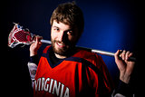 Lacrosse player holding stick. Studio shoot on the black background with blue light spot.