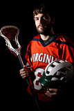 Lacrosse player holding helmet and stick.