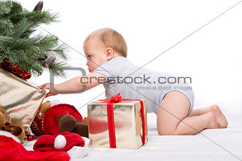 Baby boy reaching for Christmas gifts.