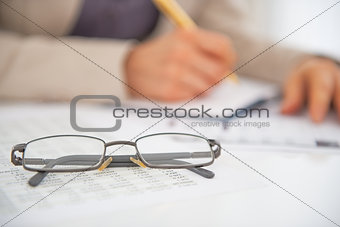 Closeup on eyeglasses on table and business woman working in bac