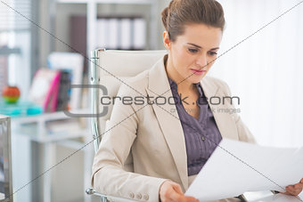 Happy business woman examining documents in office