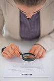Closeup on business woman exploring document with magnifying len