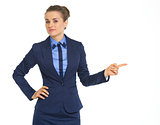 Portrait of doubting business woman pointing on copy space