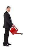 Businessman watering with red can and smiling at camera