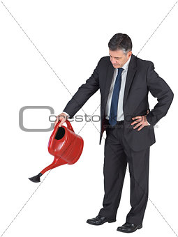 Mature businessman watering with red can