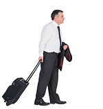 Mature businessman pulling his suitcase