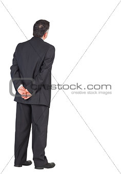 Mature businessman standing with hands behind back