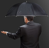 Businessman holding umbrella and reaching hand out