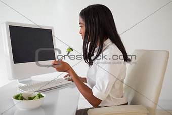 Casual pretty businesswoman eating a salad at her desk