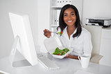 Happy pretty businesswoman eating a salad at her desk