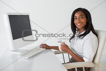 Smiling businesswoman having a coffee at her desk