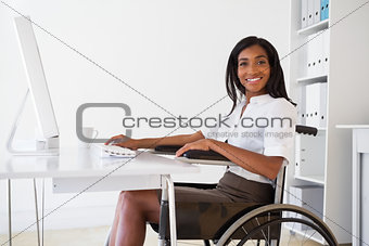 Smiling businesswoman in wheelchair working at her desk