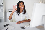 Pretty businesswoman making ok sign to camera at her desk
