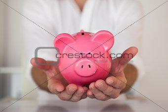Casual businessman holding piggy bank