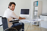 Casual businessman in wheelchair working at his desk