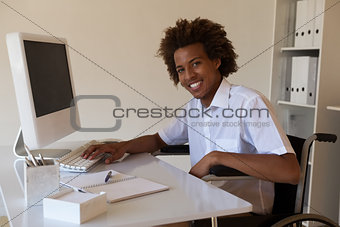 Casual happy businessman in wheelchair working at his desk