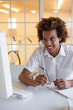 Casual young businessman sitting at his desk smiling at computer