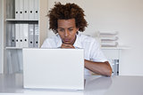 Focused casual businessman using laptop at desk