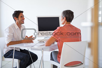 Casual business people talking at desk and smiling