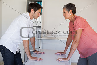 Casual business team facing off at desk