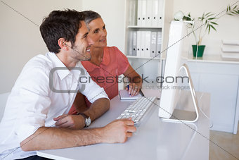 Casual business team working together at desk using computer