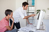 Casual business team working together at desk using computer