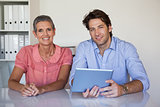 Casual smiling business team working at desk using tablet