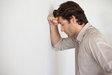 Casual worried businessman leaning head on wall