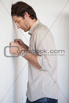 Casual worried businessman leaning on wall