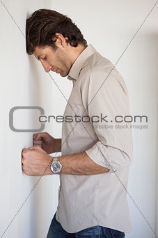 Casual worried businessman leaning on wall