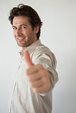Casual smiling businessman showing thumbs up to camera