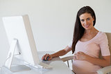Casual pregnant businesswoman smiling at camera at her desk
