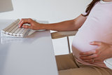 Casual pregnant businesswoman touching her bump at her desk