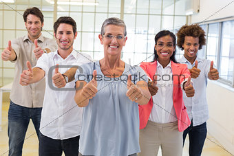 Business people giving thumbs up to camera and smiling