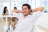 Businessman relaxing with coworkers in background