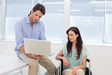 Businessman showing woman in wheelchair the laptop