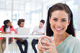 Attractive businesswoman drinking coffee with coworkers in background