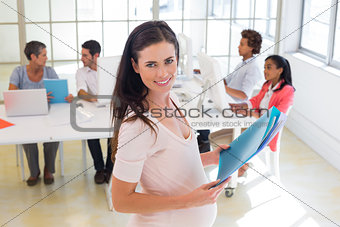 Pregnant office worker walking with files