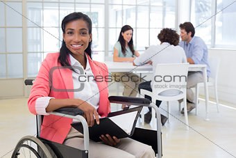 Businesswoman in wheelchair holding folder and smiling at camera