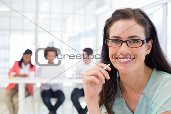 Attractive businesswoman smiling at camera with coworkers in background