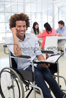 Businessman in wheelchair holding planner and smiling at camera
